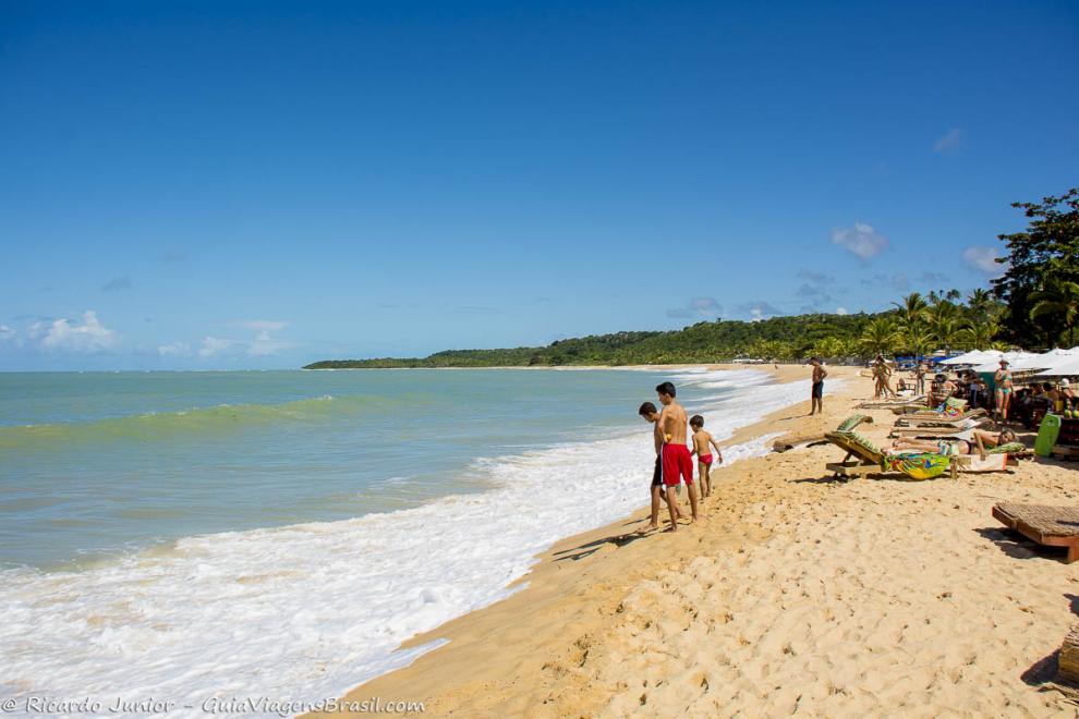 Imagem de três meninos olhando o mar.